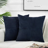 A set of two dark navy blue corduroy patchwork throw pillow covers with vertical ribbing on a white sofa.