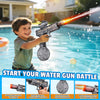 A boy is firing an automatic electric water gun into a swimming pool, creating a spray of water.