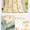 A stack of light green and beige quilted fabric featuring a delicate gold botanical print.