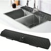 Black silicone faucet mat and sink splash guard placed over a stainless steel kitchen sink.