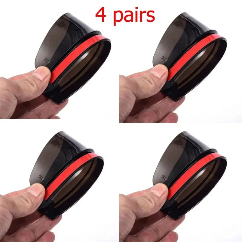 Four pairs of black and red carbon fiber car side mirror rain and sun visors being held by a hand.