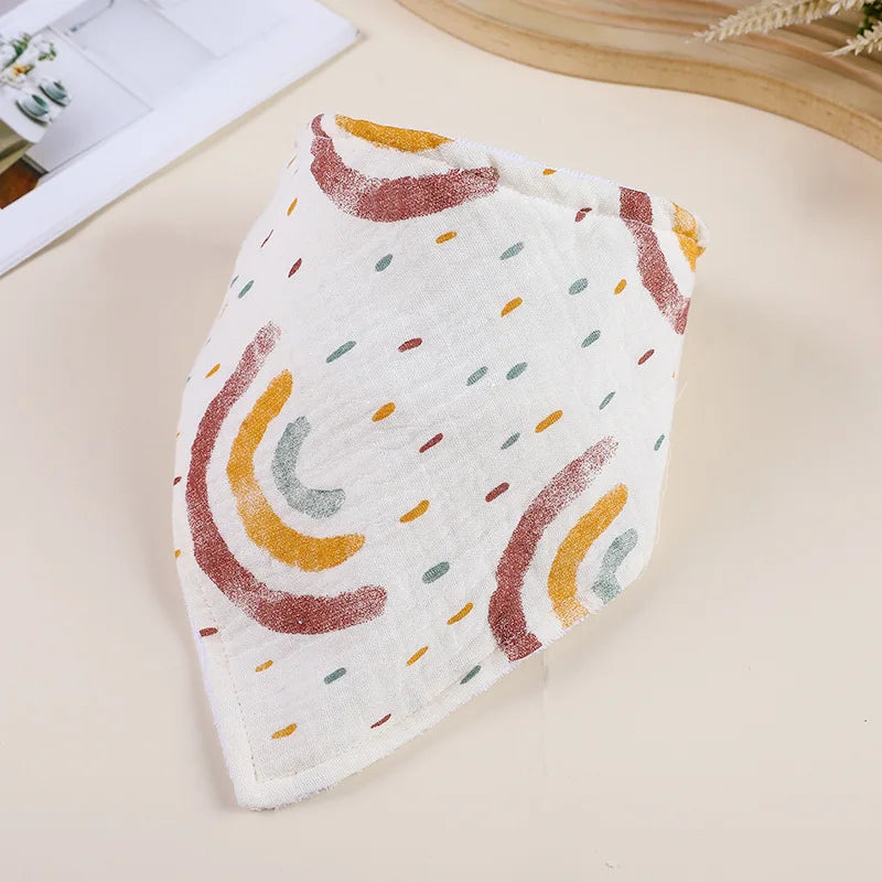 A white cotton baby bib with a pattern of orange, brown, and green abstract stripes.