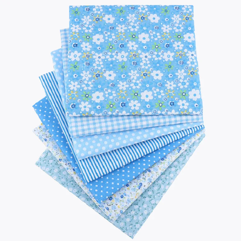 A bundle of light blue cotton fabric squares featuring a floral dot pattern for patchwork and quilting.