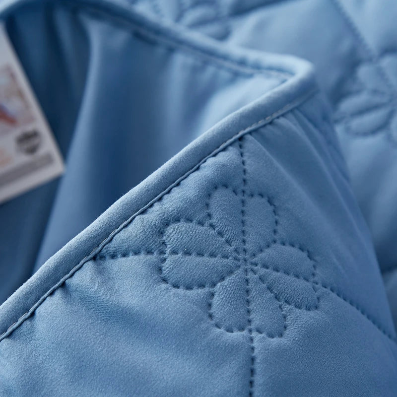 Close-up of a light blue quilted mattress protector fabric detail.