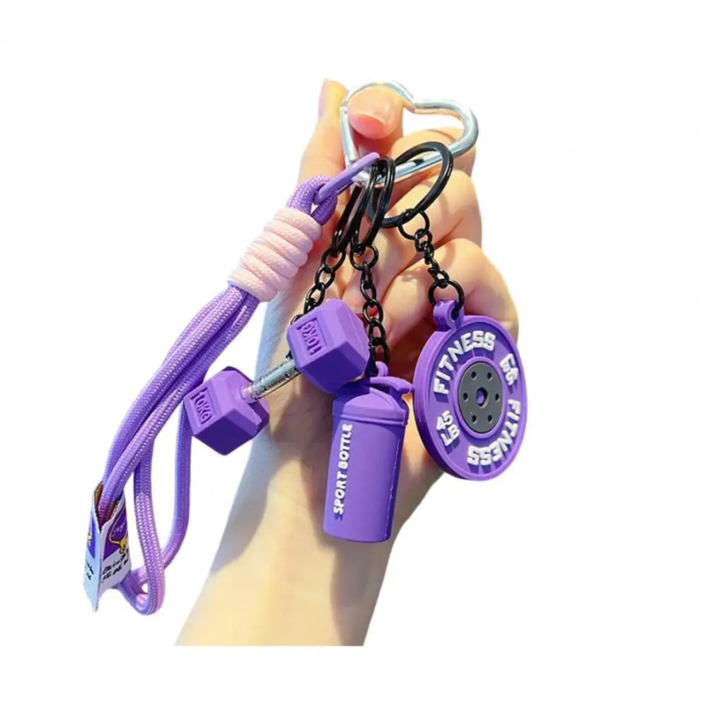 A hand holds a purple fitness keychain with a silver clasp and various purple components.