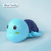 A light blue wind-up swimming turtle toy with a dark blue shell resting on a light blue surface.