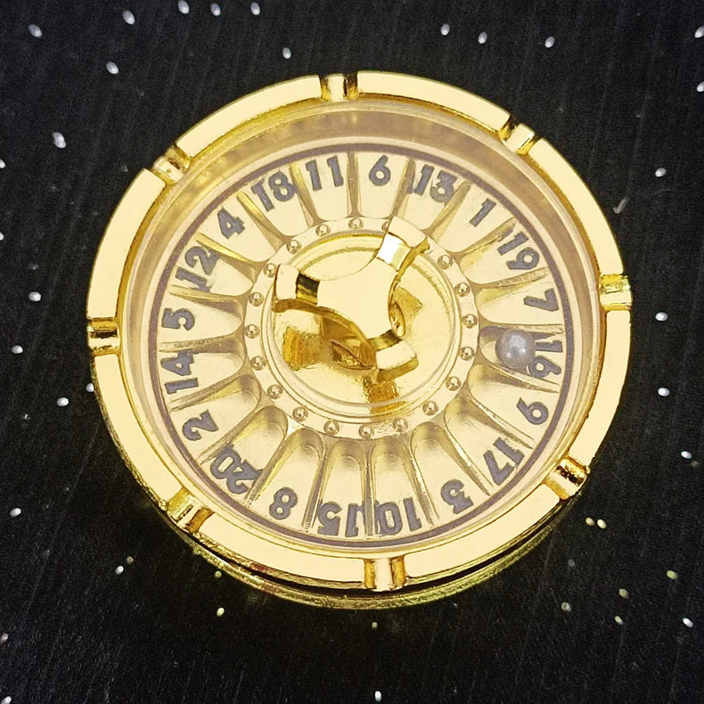 A round, gold-colored metal roulette dice with numbered markings and a central pivot.