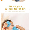 A baby is using a blue waterproof feeding bib to eat, demonstrating its stain and water resistance.