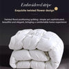 A stack of premium white goose down comforters with an embroidered stripe design.