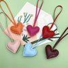 A collection of heart-shaped PU leather keychains in various colors, including peach, purple, red, blue, and brown.