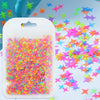 A clear plastic pouch filled with colorful holographic star sequins scattered on a white surface.