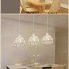 Three crystal single-head ceiling lamps hanging above a modern dining table.