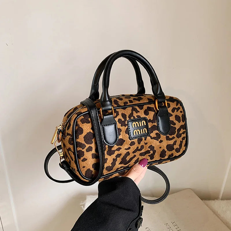 A brown and black leopard print retro mini hobo satchel bag being held by a hand.