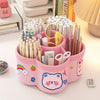 A pink rotating desk organizer holds various pens, pencils, and writing supplies.