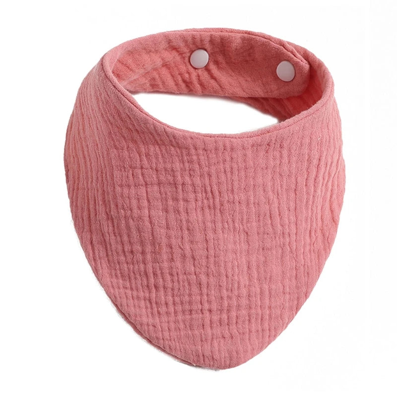 A pink organic cotton muslin baby bib with a textured, absorbent band.