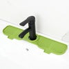 A black silicone faucet mat with a handle and splash guard is placed on a white countertop.