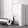 Roll of self-adhesive marble wall sticker in white and gray veining against a white wall.