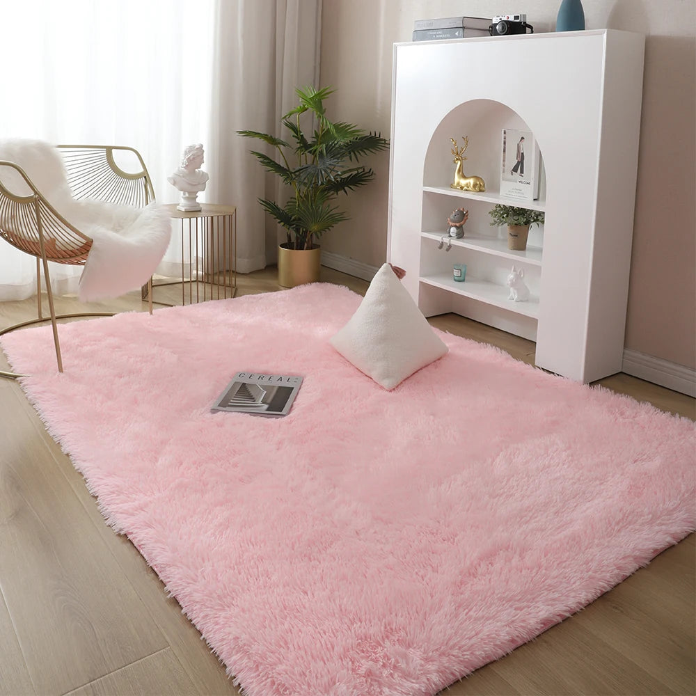 A fluffy pink Nordic furry accent rug placed on a light wood floor next to a white shelving unit.