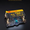 A yellow Kodak microSD card is shown emerging from a dark surface with bright electrical sparks.