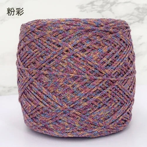 A ball of metallic silk crochet yarn with a shimmering purple and gold thread for knitting and macrame.
