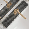 A brass faucet mat with a spiral design is placed on a white countertop.