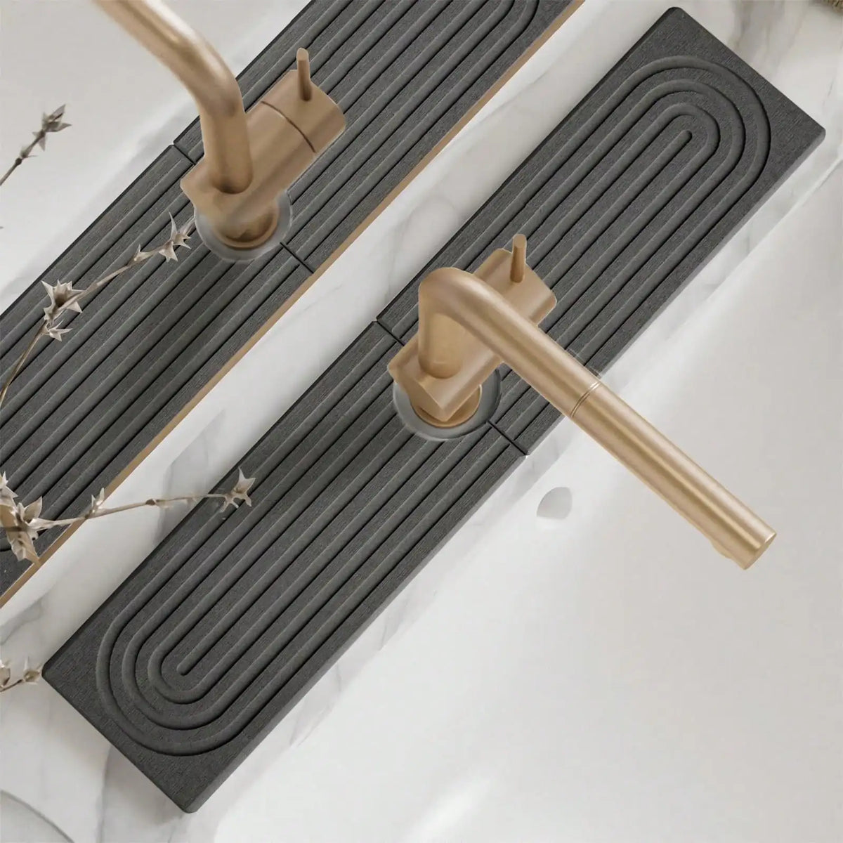 A brass faucet mat with a spiral design is placed on a white countertop.