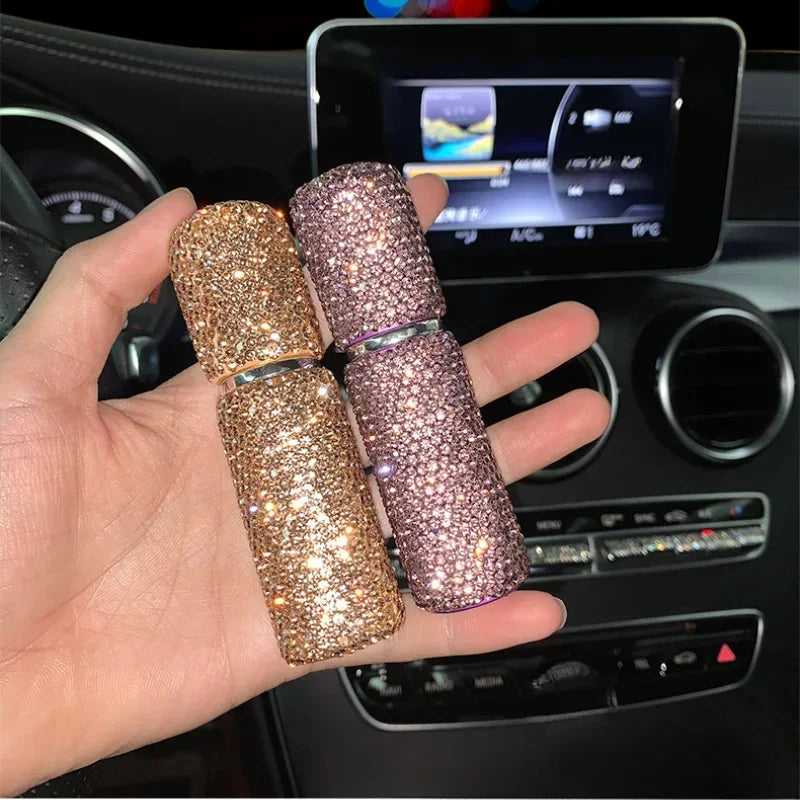 A hand holds three gold and pink refillable glass perfume atomizers in a car interior setting.