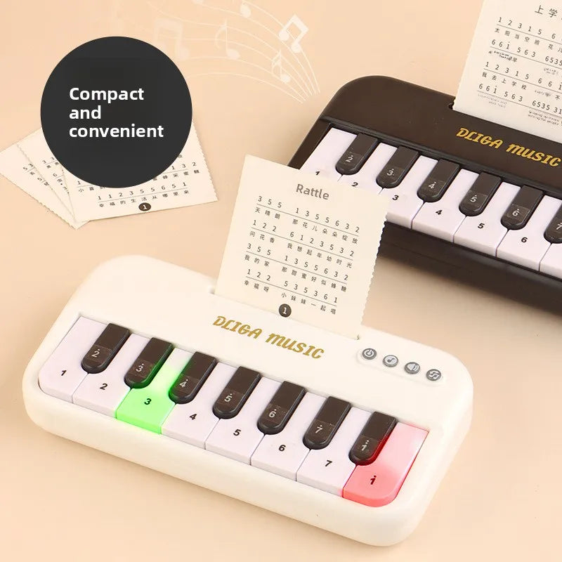 A white mini 15-key electronic keyboard piano with colorful lights and a rattle sheet is shown on a light background.