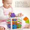 A baby is playing with a white plastic toy that features various colored shapes and balls for sensory development.