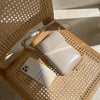 A light beige vintage PU leather crossbody shoulder bag resting on a woven wooden tray.
