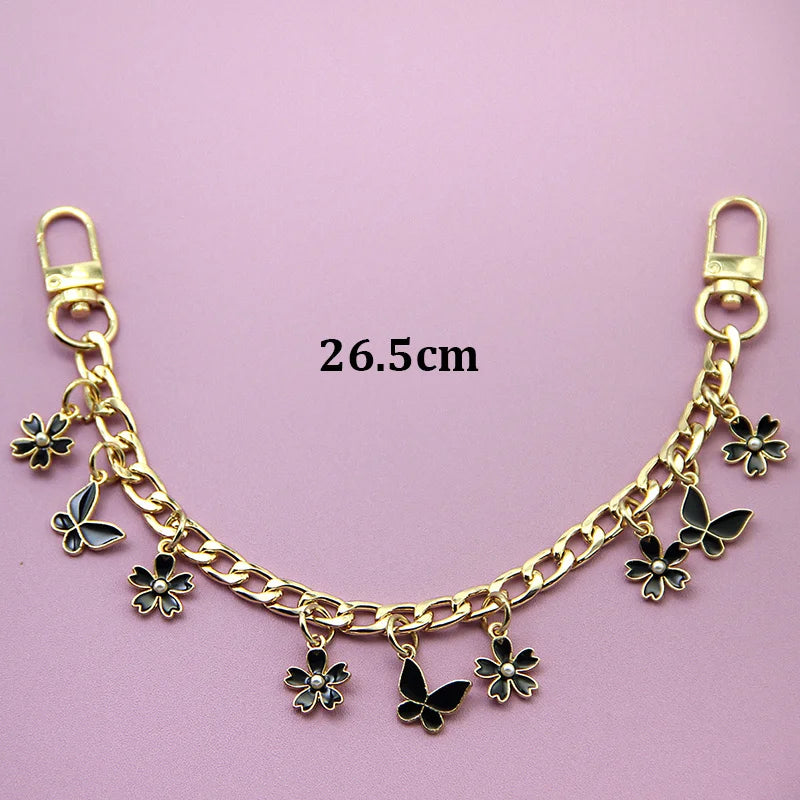 Gold chain necklace with black butterfly and flower charms, measuring 26.5cm.