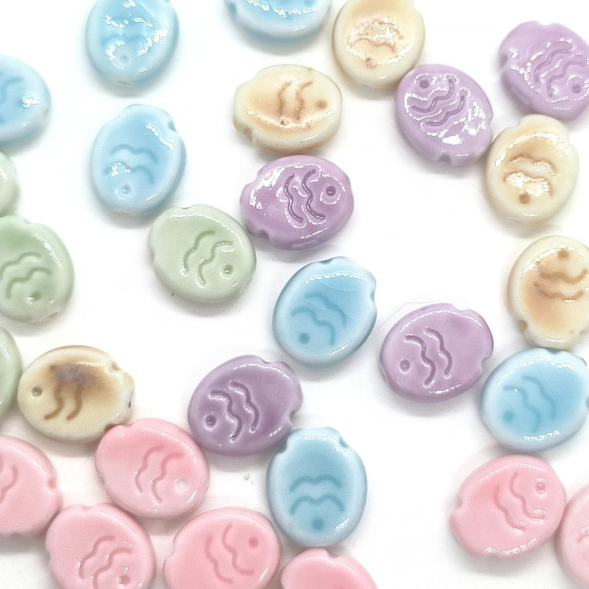 A collection of handcrafted ceramic fish beads in various pastel colors including blue, purple, and pink.