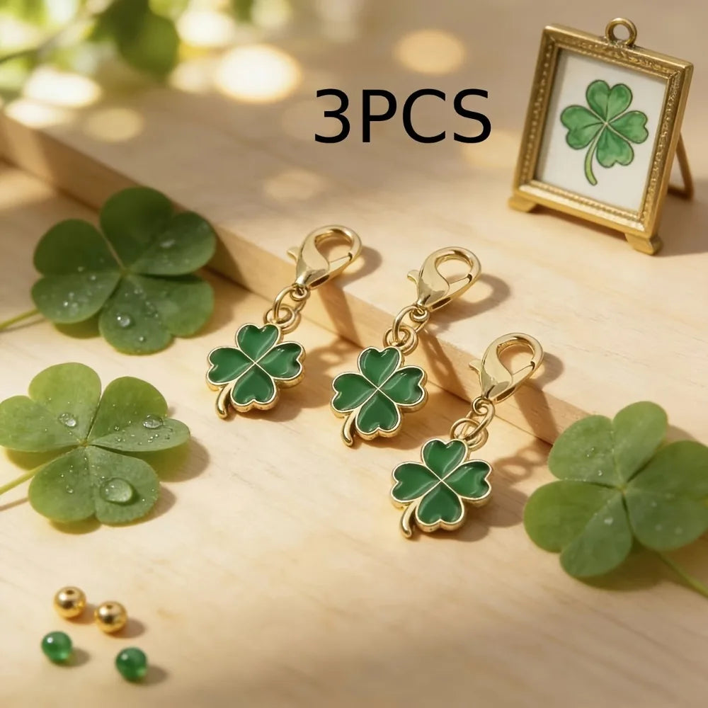 Three green four-leaf clover keychain charms displayed on a wooden surface with a framed clover.