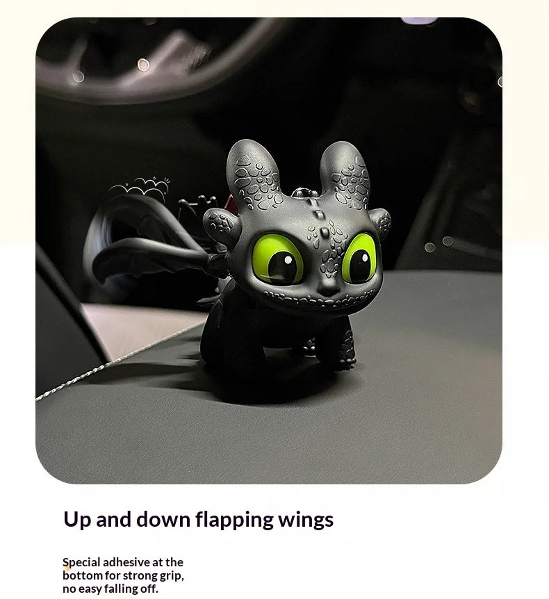 A black Toothless car ornament featuring glowing green eyes and up and down flapping wings.