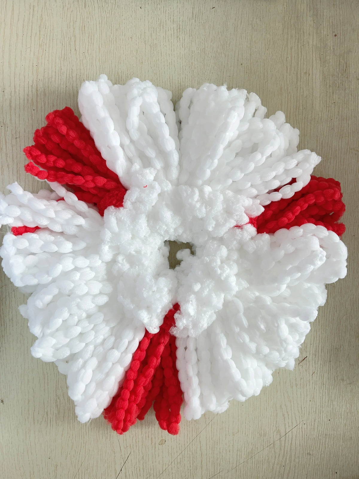 A white and red floral wreath made of fluffy white and red yarn or fiber for mop pad replacements.
