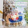 A hand holds a camera-shaped automatic bubble machine with lights and music, surrounded by numerous bubbles.
