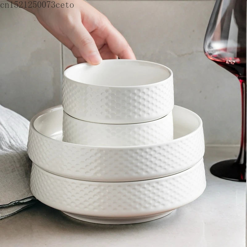 A stack of white ceramic soup bowls is shown with a hand placing a bowl on top.