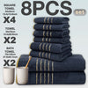 A set of eight dark blue bath towels with gold stripes stacked and displayed on a light gray background.