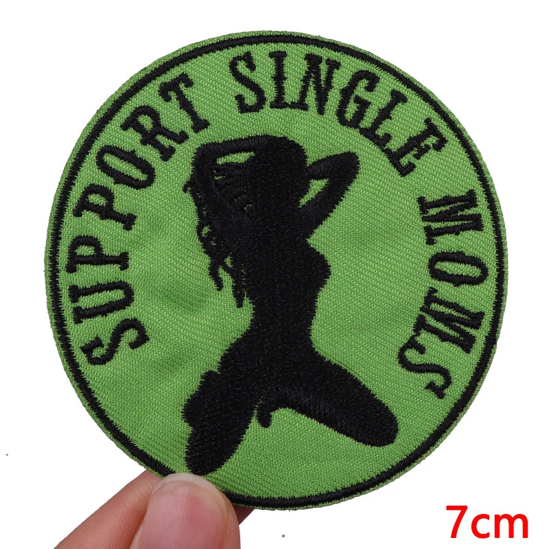 A round, olive green embroidered patch featuring a silhouette of a woman and the text SUPPORT SINGLE WOMENS