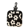 Black mini coin purse with a white floral pattern and a black strap.