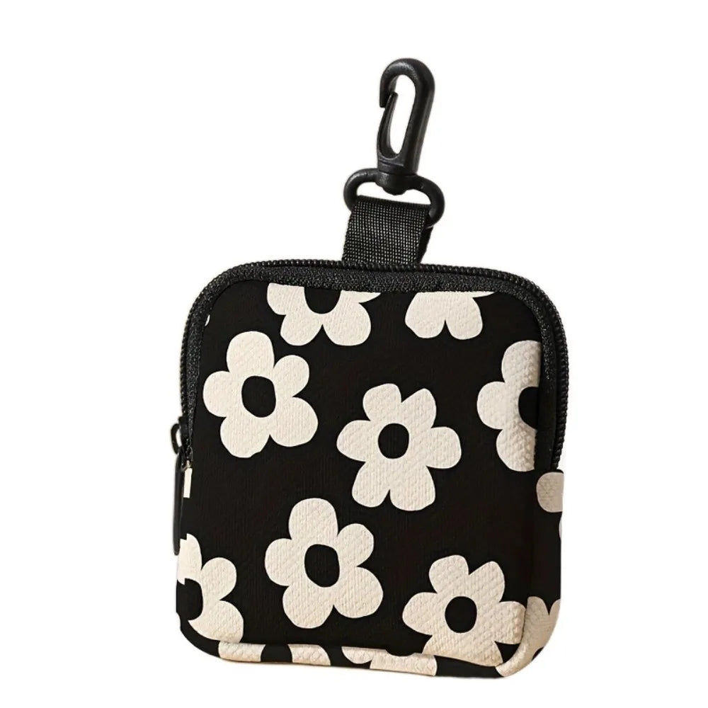 Black mini coin purse with a white floral pattern and a black strap.