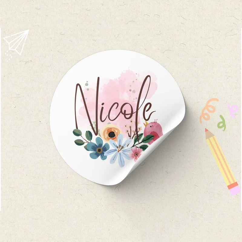 A white sticker with the name Nicole written in elegant script surrounded by pink and blue floral elements.