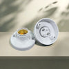 A white E27 screw cap light bulb holder with a gold-colored bulb visible inside, placed on a light surface.