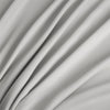 A close-up of a flowing, light gray bamboo flat sheet fabric draped in soft folds.