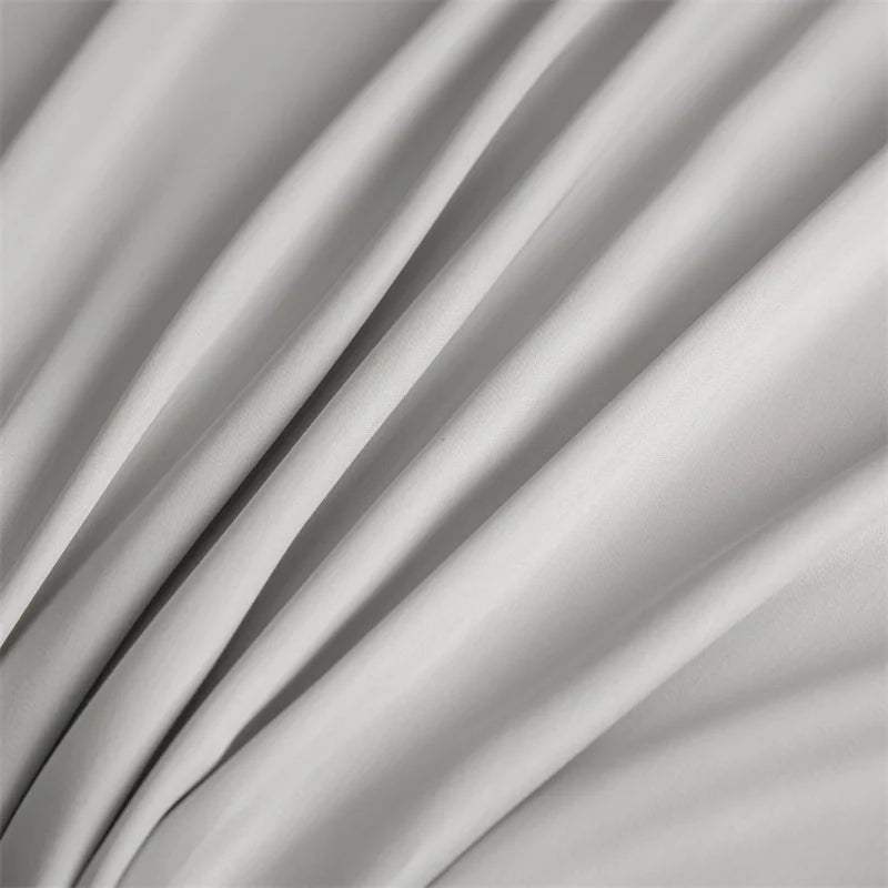 A close-up of a flowing, light gray bamboo flat sheet fabric draped in soft folds.
