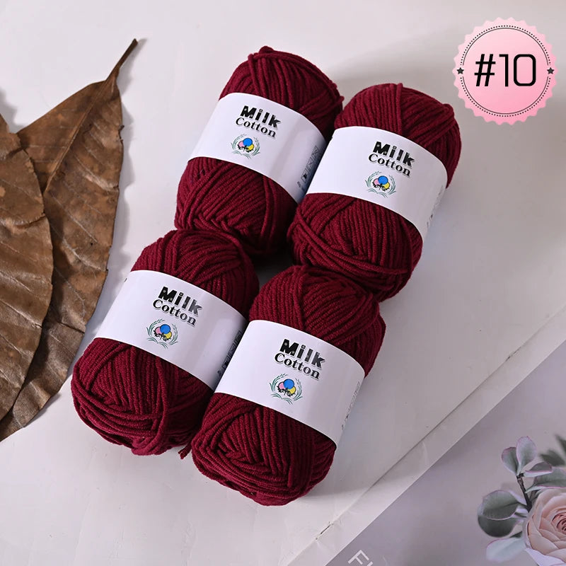 A stack of deep red Milk Cotton yarn skeins for knitting and crochet projects.