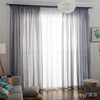 Grey sheer voile curtains with rod pockets filtering light through a window.