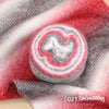 Roll of colorful gradient cake yarn showing red and white swirls on a gray fabric background
