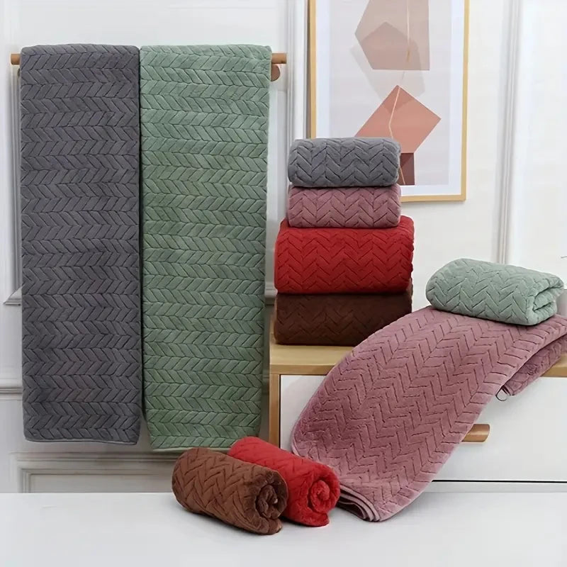 A stack of various colored bath towels, including gray, green, and pink, are displayed on a shelf.