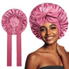 A woman models a pink satin silk sleep bonnet, showing the fabric and design.